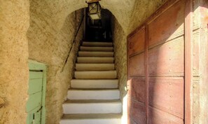 Eine Treppe führt zu einer Tür, über ihr hängt ein Laternenlicht.