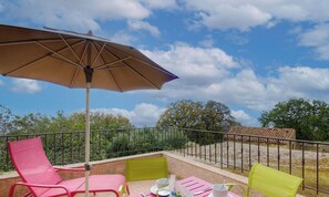 Ein Balkon mit Tisch, Stühlen und Sonnenschirm.
