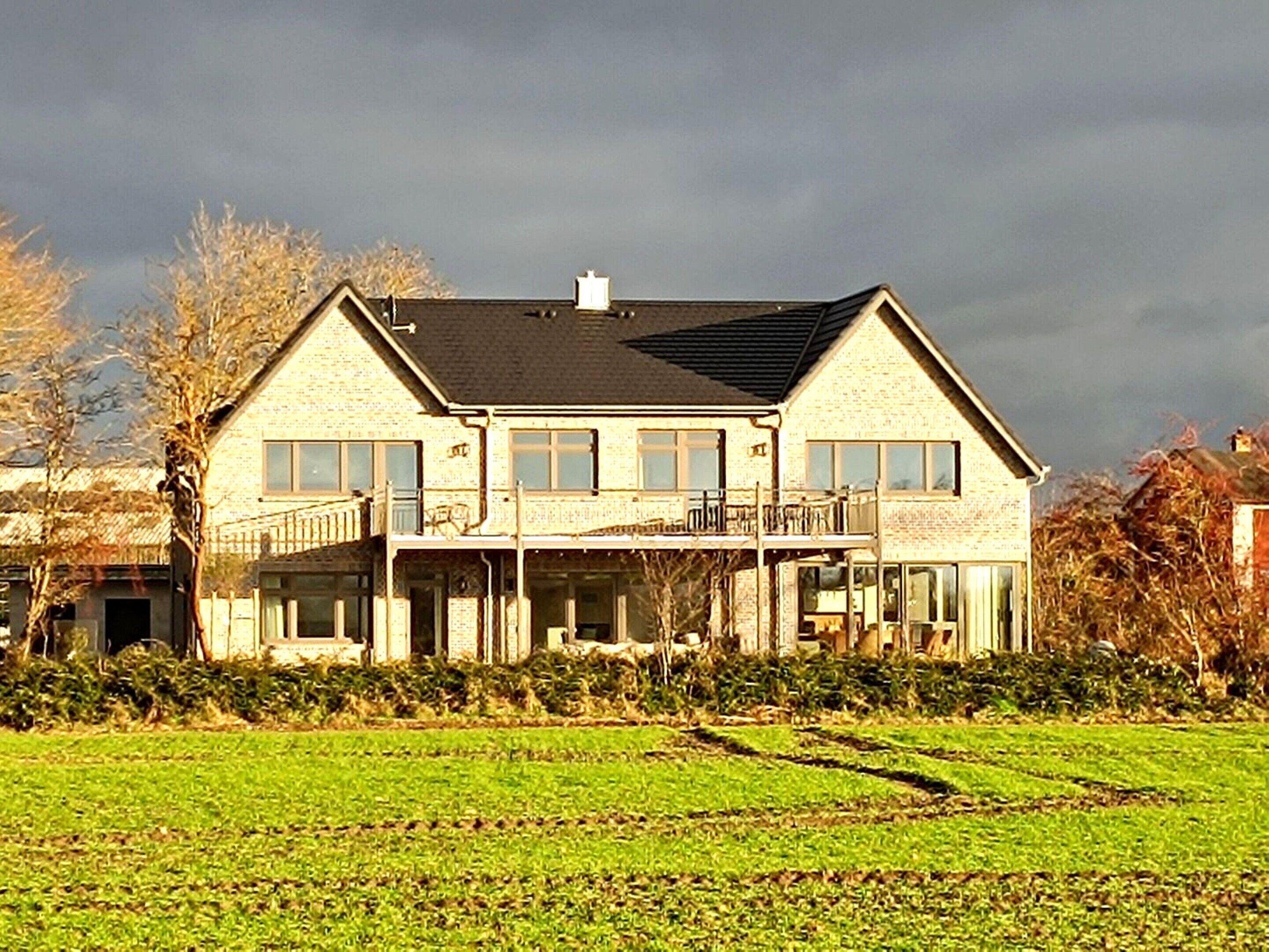 A two-story house with a balcony, a garage, and a large front lawn.
