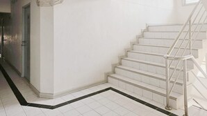 A staircase with white tiles and metal railings, leading to an upper floor. - H-Hub BBT (Bang Bua Thong)