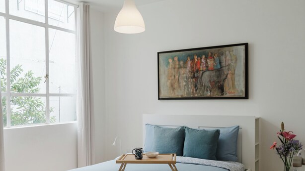 A bedroom with a bed, a bedside table, a window, and a hanging light fixture. - Beautiful 1BR in the heart of Condesa featuring a spacious equipped kitchen, cozy TV lounge, full bathroom, washer, and comfortable bedroom. Sofa bed available for 1 child. Perfect for enjoying one of CDMX’s best neighborhoods. (Cuauhtémoc)