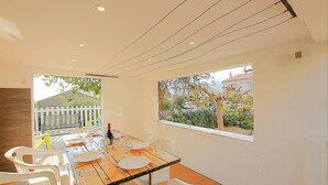 A dining area with a table set for four, a view of the garden, and a white fence outside. - Stay in the heart of an authentic village, just a few kilometers from the beaches. (MONACIA D'AULLENE)