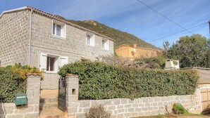 A stone house with a tiled roof, a small garden, and a hillside in the background. - Stay in the heart of an authentic village, just a few kilometers from the beaches. (MONACIA D'AULLENE)