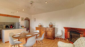 A dining area with a wooden table and chairs, a kitchen with appliances, a fireplace, and a mirror on the wall. - Stay in the heart of an authentic village, just a few kilometers from the beaches. (MONACIA D'AULLENE)
