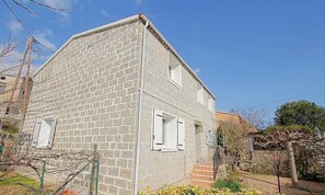 Ein zweistöckiges Steinhaus mit einer kleinen Veranda und einer Treppe zum Eingang.