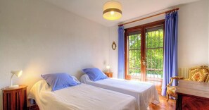 Ein Zimmer mit zwei Betten, einem Tisch und einem Stuhl.