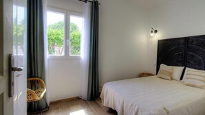 Ein Schlafzimmer mit Bett, Stuhl, Fenster und einer Wandleuchte.