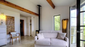 Ein Wohnzimmer mit einer Couch, einem Holzstuhl, einer Steinwand, einem Kamin und einem Fenster.