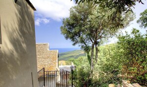 Ein Steinhaus mit Blick auf das Meer und die umliegende Vegetation.