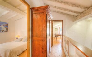 Ein Schlafzimmer mit Holztür, einem Bett, einem Nachttisch und einem Bild an der Wand.