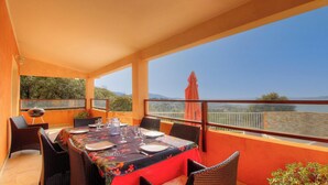 An outdoor dining area with a table set for two, surrounded by wicker chairs, overlooking a body of water with a view of the landscape. - A Milella1 - VIGGIANELLO (VIGGIANELLO)