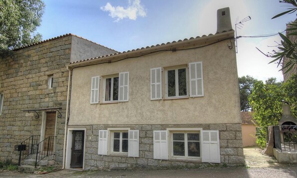 A two-story stone house with white shutters, a small porch, and a chimney. - Frisella - MONACIA D'AULLENE (MONACIA D'AULLENE)