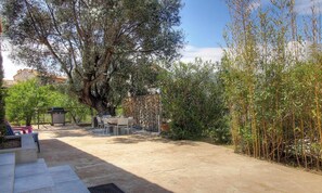 Eine Terrasse im Freien mit Esstisch und Stühlen, umgeben von Bäumen und Bambuspflanzen.
