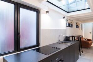 Eine moderne Küche mit schwarzem Arbeitsplatz, integriertem Herd und einem Fenster mit Jalousien.