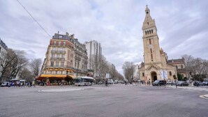 A street view with a prominent clock tower and a building with a sign reading 'ZEEVE.' - Loft Design Alésia - Island bath - Métro 1mn (Paris)
