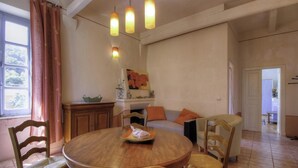 Un comedor con una mesa redonda, sillas, un aparador y un cuadro en la pared.