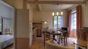 Cocina compacta con comedor, cama y televisor.