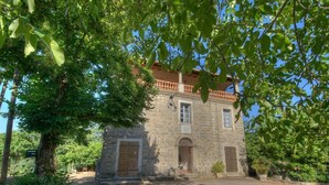 Un edificio de piedra con un balcón, rodeado de árboles.