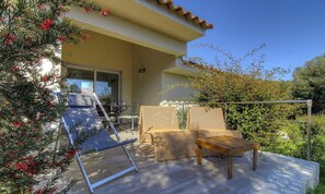 Eine Terrasse mit Gartenmöbeln, einer Pergola und Blick auf ein Gebäude.