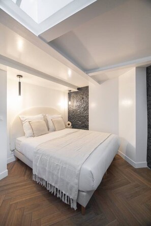 Ein Schlafzimmer mit einem großen Bett, einer Wand aus Stein und einem Oberlicht.