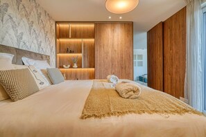 A bedroom with a large bed, wooden paneling, a built-in shelf with decorative items, and a view of the outside. - Bois de Vincennes - Luxury & Balcony - 4P (Saint-Mandé)