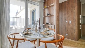 A dining area with a round table, four wooden chairs, and a view of the outside. - Bois de Vincennes - Luxury & Balcony - 4P (Saint-Mandé)