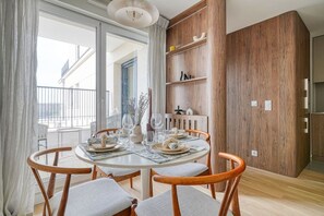 A dining area with a round table, four wooden chairs, and a view of the outside. - Bois de Vincennes - Luxury & Balcony - 4P (Saint-Mandé)