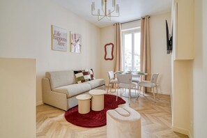 Una sala de estar con un sofá, una mesa redonda de centro y un comedor con sillas y una mesa.
