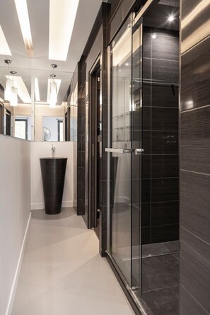 A modern bathroom with a glass shower enclosure, a black sink, and a light-colored floor. - Spacious 4BR in Paris - 3 Baths - 10 Guests (Montreuil)