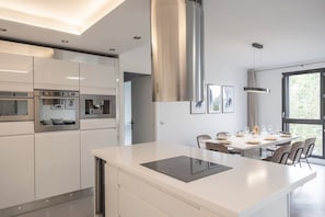 A modern kitchen with built-in appliances, a dining area with a large window, and a minimalist design. - Spacious 4BR in Paris - 3 Baths - 10 Guests (Montreuil)