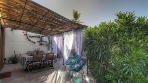 Eine Terrasse im Freien mit einem Holztisch und -stühlen, einer Pergola und üppigem Grün.