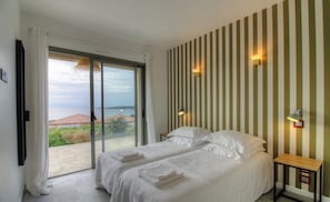 Ein Schlafzimmer mit zwei Betten, einer Schiebetür zum Balkon und einer Wand mit Streifenmuster.