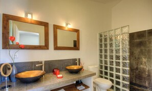 Ein Badezimmer mit zwei Holzwashbecken, einer Duschkabine aus Glas und einem Spiegel über dem Waschbecken.