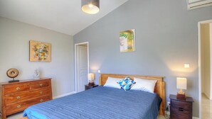 A bedroom with a bed, wooden dresser, nightstands, and wall art. - Serenity - SOTTA - Gîte (SOTTA)