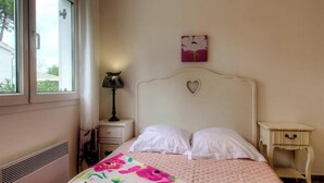 Un dormitorio con una cama, una mesita de noche, una lámpara, una ventana y un adorno en la pared.