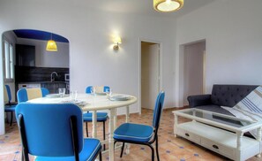 Ein Essbereich mit einem runden Tisch, blauen Stühlen und einer Couch.