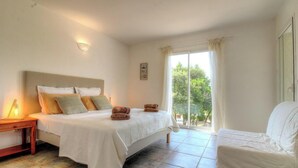 Ein Schlafzimmer mit Bett, Nachttisch, Stuhl und Blick auf Grün.