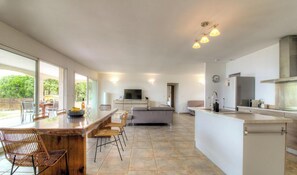 Eine moderne Küche mit Essbereich, einem Fernseher und einem großen Fenster.