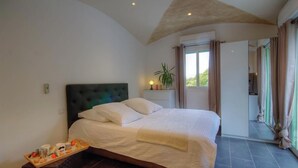 Une chambre à coucher avec un lit, une table de chevet, une fenêtre et une vue sur l’extérieur.