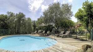 Une piscine avec des chaises longues et un kiosque.