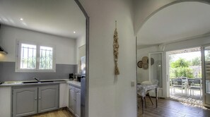A kitchen with a window, a dining area with a table and chairs, and a view of the outside. - Bonifacio - SOTTA - Gîte (SOTTA)