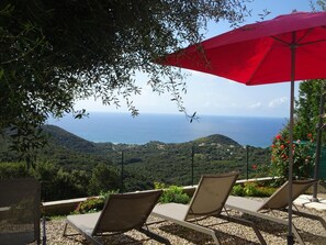 A terrace with two lounge chairs and a red umbrella, overlooking a coastal landscape with hills and the sea. - L'Alivetu - FARINOLE (FARINOLE)