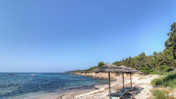 A beach with clear blue water, a few boats, and a row of beach umbrellas. - Les Pieds dans l'eau (COTI CHIAVARI)
