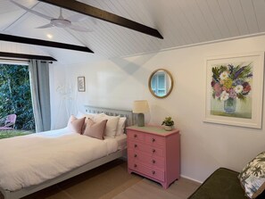 A bedroom with a bed, a dresser, a mirror, and a framed floral artwork on the wall. - The Pink Door - 3 Bedroom Cottage - Walking Distance to Town (Maleny)