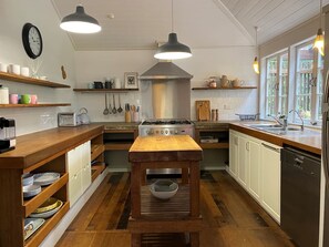 Een keuken met houten kastjes, een centraal eiland, een fornuis en hanglampen.