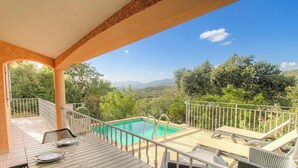 Ein Poolbereich mit Blick auf die Landschaft, eine überdachte Terrasse und Sitzmöglichkeiten im Freien.
