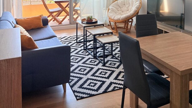 A modern living room with a sofa, dining table, chairs, a TV, and a balcony with a view. - Beautiful setting with a terrace overlooking the sea (Saint-Cyprien)