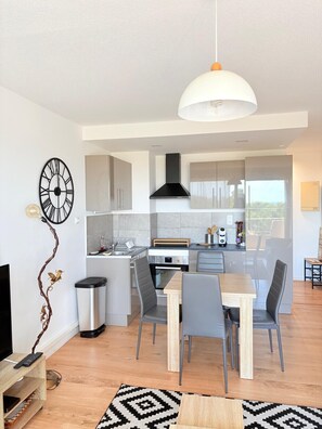 A modern kitchen with a dining area, a TV, and a decorative wall piece. - Beautiful setting with a terrace overlooking the sea (Saint-Cyprien)