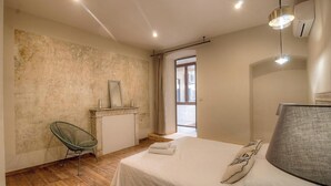 Une chambre à coucher avec un lit, une chaise, une coiffeuse avec un miroir et une fenêtre.