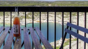 Une bouteille de boisson sur une table en bois, avec vue sur un paysage côtier.